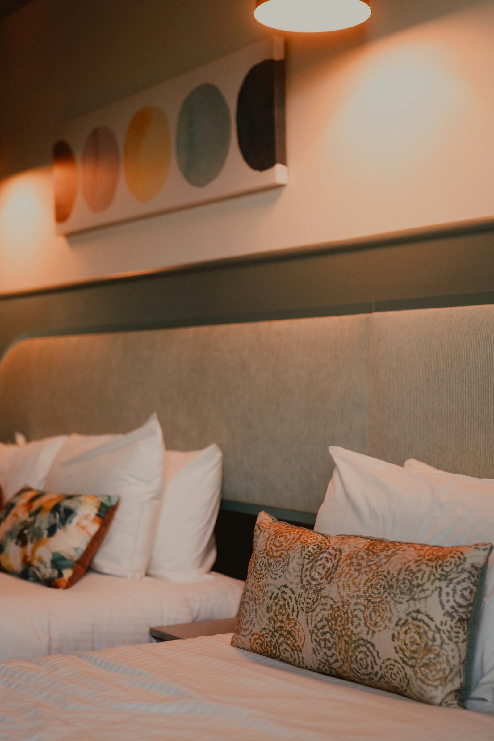 Sıcak aydınlatmalı otel odasında yatak ve yastık detayı